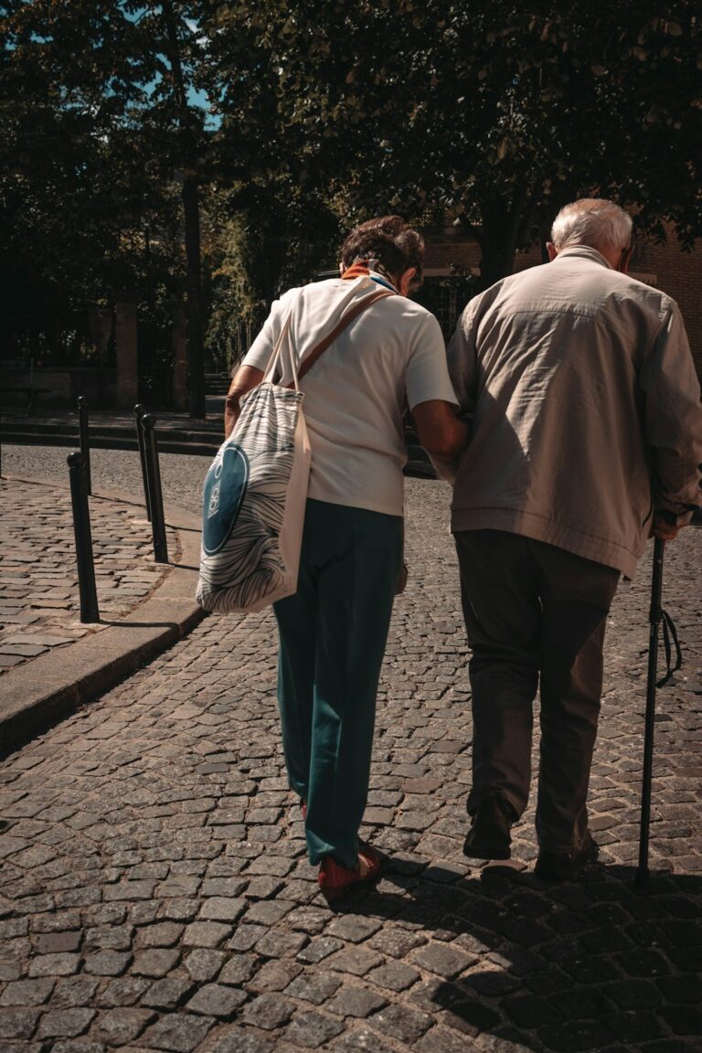 A caring professional and a smiling senior talk together in a cozy, sunlit living room.