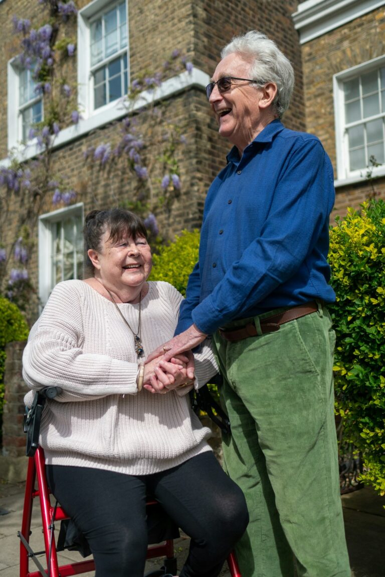 A caregiver helping an older adult with meal preparation in a bright kitchen.