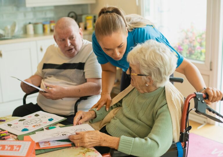 A mature caregiver presenting identification and paperwork to a staff member at a desk in a bright, welcoming office.
